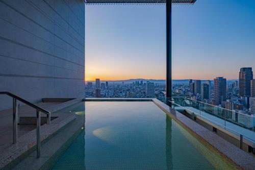 a swimming pool on top of a building with a city skyline at Candeo Hotels Osaka The Tower in Osaka