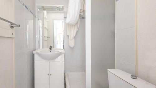 une salle de bain blanche avec un lavabo et un miroir dans l'établissement PRIMAVERA - 301 - Appt Lumineux 4 pers, au Cap d'Agde