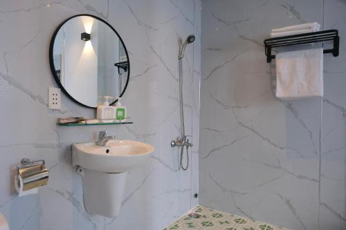 uma casa de banho branca com um lavatório e um espelho em Nicecy Hotel - Yersin Street em Cidade de Ho Chi Minh