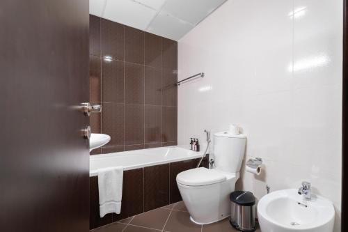 a bathroom with a toilet and a tub and a sink at Nasma Luxury Stays - Luxurious Coastal Living Bab Al Bahr Residences in Ras al Khaimah