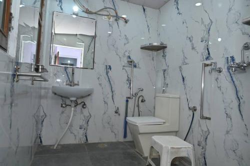 La salle de bains est pourvue de toilettes, d'un lavabo et d'un miroir. dans l'établissement Colonel's Cottage, à Jaipur