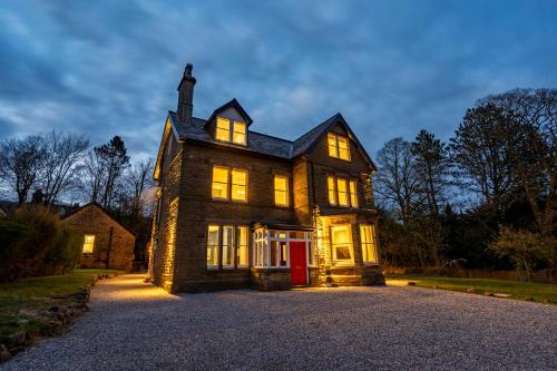 una gran casa de ladrillo con sus luces encendidas en Calming Crescent, en Buxton