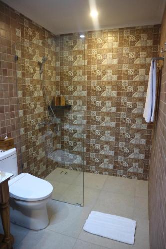 a bathroom with a toilet and a glass shower at De Umah Bali Eco Tradi Home in Bangli