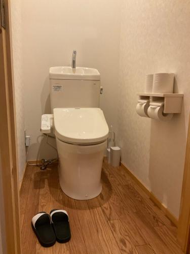 La salle de bains est pourvue de toilettes et d'une paire de chaussons. dans l'établissement Retreat Camp Mahoroba, à Fujikawaguchiko