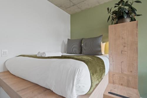 a bedroom with a white bed with a plant on the wall at Six On N Apartments - Managed by Propr in Cape Town