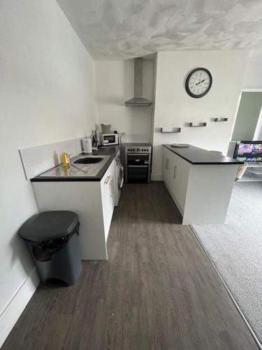 a kitchen with white counters and a clock on the wall at Skegness Town Centre Apartment 1 in Lincolnshire