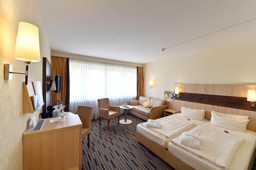 ein Hotelzimmer mit einem Bett und einem Wohnzimmer in der Unterkunft Kurpark-Hotel in Bad Dürkheim