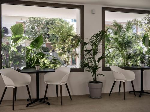 two tables and chairs in a room with plants at Bond Smart Living Suites in Athens