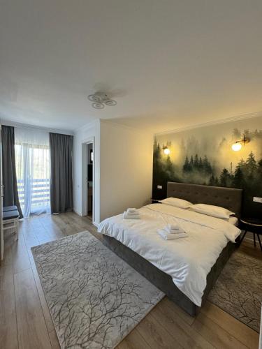 a bedroom with a large bed with a painting on the wall at Flori de Tei Maramures in Săcel
