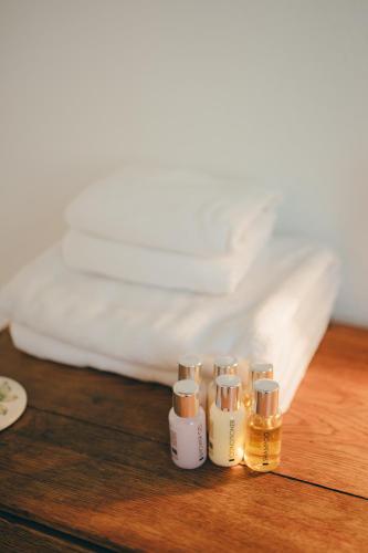 four bottles of essential oils sitting on a table next to a bed at Cozy Garden Rooms in Chevilly-Larue