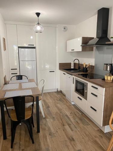 une cuisine avec des armoires blanches, une table et une cuisinière dans l'établissement Résidence Domaine de Lumière, à Saint-Jean-de-Monts