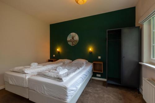 een slaapkamer met een groot bed met een groene muur bij Vakantiehuis Zeepeertje, Vroondijk in Vrouwenpolder in Vrouwenpolder
