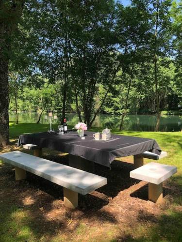 a table with a black table cloth and two benches at Gîte “Les reflets de la Charente” in Condac
