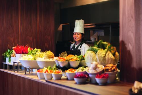 a chef behind a counter with bowls of vegetables at Mövenpick Hotel Zürich-Regensdorf in Regensdorf