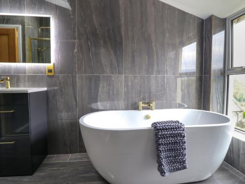 a bathroom with a white tub and a mirror at Trysorau Bach 2 in Llanrwst