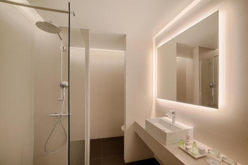 a bathroom with a sink and a shower with a mirror at NH Collection Milano Touring in Milan