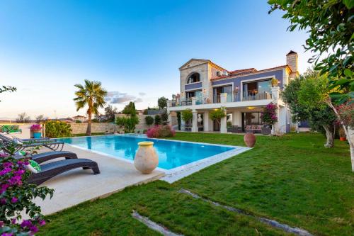 a house with a swimming pool in front of a yard at VillaSunset with Magnificent Sea View in Çeşme