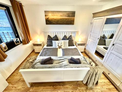 a bedroom with a large white bed with two windows at Gemütliches Alpenblick BERG-Bungalow + großer GARTEN + NETFLIX! in Schöfweg