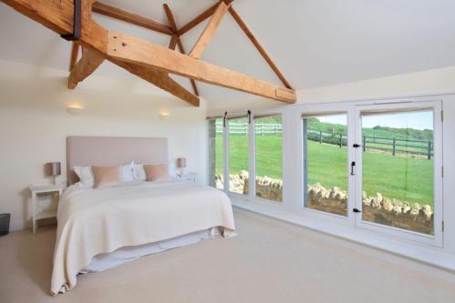 a bedroom with a bed and large windows at Clayhanger Lodge in Abbotsbury