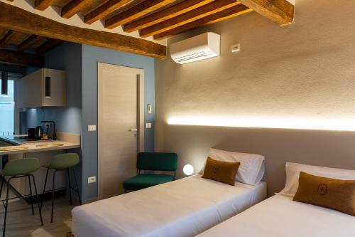 two beds in a small room with a kitchen at Palais Bernadette in Parma