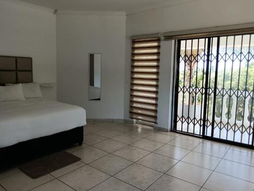 een slaapkamer met een bed en een glazen schuifdeur bij The Rose on Fairway in Durban