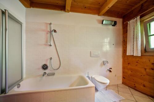 a bathroom with a bath tub and a toilet at Ferienhaus Rauchegg - Bergblick in San Pancrazio dʼUltimo