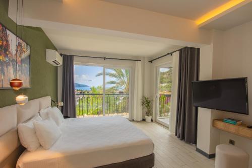 a bedroom with a bed with a television and a balcony at Morina Deluxe Hotel in Oludeniz
