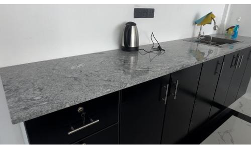 a granite counter top in a kitchen with black cabinets at Shakin Shasha Beach House/neithalbeachcity in Jaffna