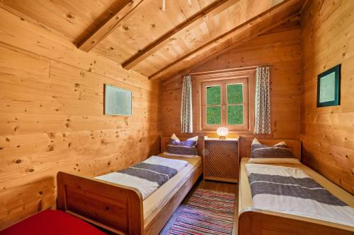 two beds in a log cabin with a window at Ferienhaus Rauchegg - Bergblick in San Pancrazio dʼUltimo