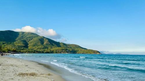 a beach with the ocean and mountains in the background at COBI’s Home in Cam Lâm