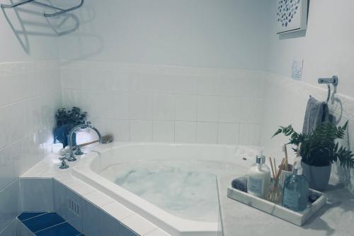 een witte badkamer met een bad met planten bij U2 at Moana Beach Esplanade - Exclusive 2 Bdrm Apt - WiFi - Spa - Pet Friendly in Moana