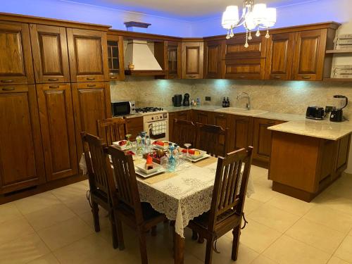 eine Küche mit einem Tisch und Stühlen sowie eine Küche mit Holzschränken in der Unterkunft KIMRAY Boutique Apartment - Indulge in Comfort, Embrace Tranquility in Marsaskala