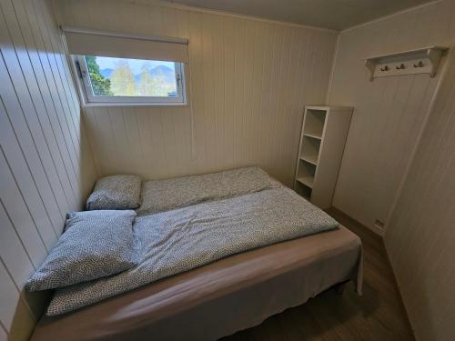 Habitación pequeña con cama y ventana en Apartment with a view close to The Pulpit Rock en Jørpeland