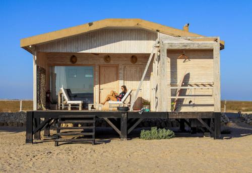 a woman sitting in a chair in a house on the beach at Océan Vagabond Lassarga in Dakhla