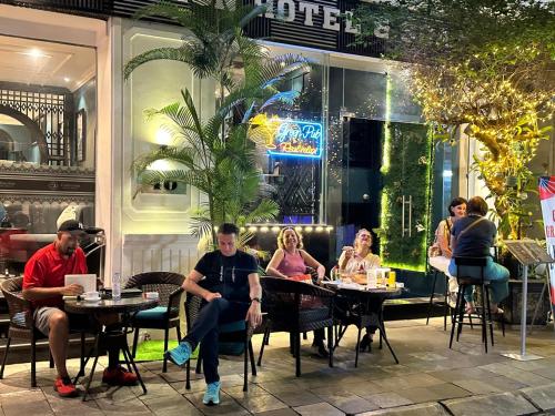 um grupo de pessoas sentadas em mesas em um restaurante em Grande Collection Hotel & Spa em Hanói