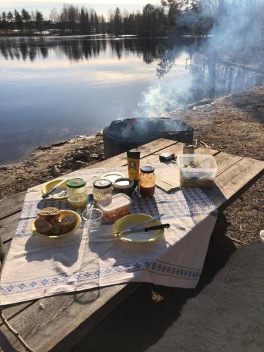 una mesa de picnic con comida junto a un lago en Talo Kainuun korvessa Kiekinkoskella, en Kuhmo