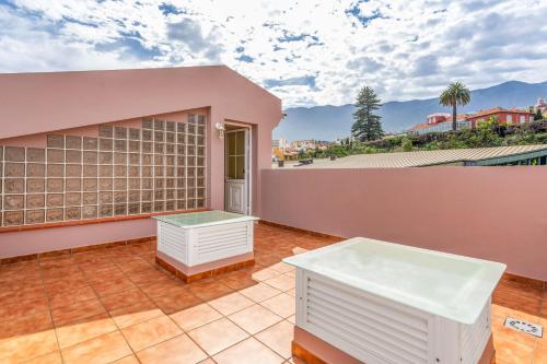 a patio with two tables on a pink house at Villa Teide in La Orotava