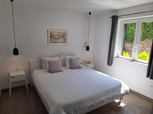 a bedroom with a white bed with two windows at Mimi in Hvar