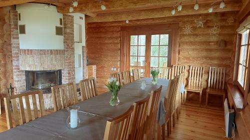 a dining room with a long table with chairs and a fireplace at Jaunsētas in Alūksne