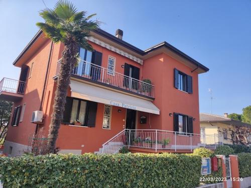a red house with a palm tree in front of it at Casa Patrizia B&B cir in info in Sirmione