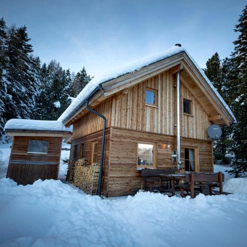 a log cabin with a table in the snow at Almrausch Lodge Grohmann in Turracher Hohe
