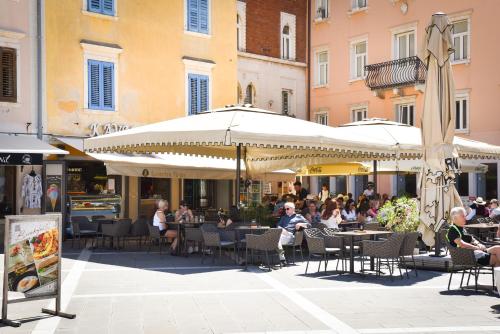 a group of people sitting at an outdoor restaurant with umbrellas at JR Piran B&B in Piran