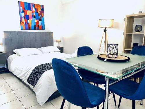 Schlafzimmer mit einem Bett und einem Tisch mit blauen Stühlen in der Unterkunft Saronikos in Piräus