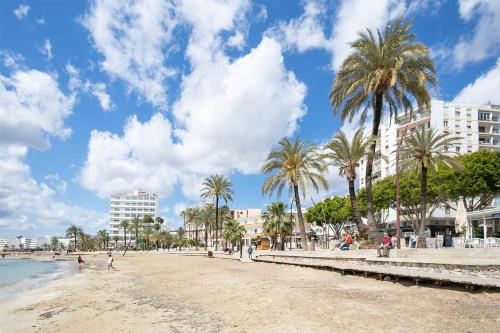 a beach with palm trees and buildings and the ocean at Suncoast Ibiza Hotel - Adults Only - in Ibiza Town