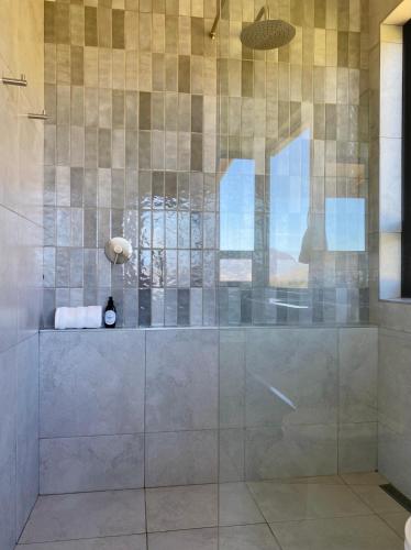 a bathroom with a shower with a glass wall at Sneeukop Mountain Cottage in Paarl