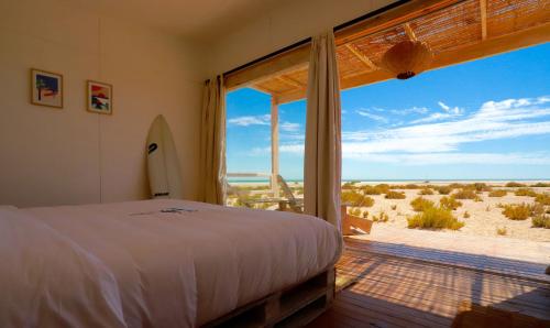 a bedroom with a bed and a view of the beach at Océan Vagabond Lassarga in Dakhla