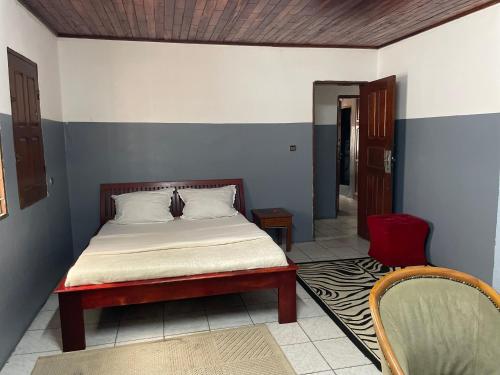 sypialnia z łóżkiem i czerwonym krzesłem w obiekcie Couba Club w mieście Duala