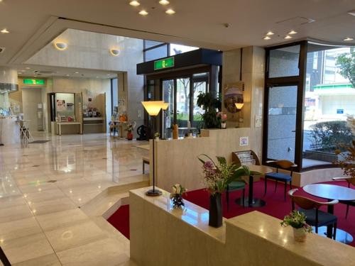 a lobby with tables and chairs in a building at Sky Hotel in Matsuyama