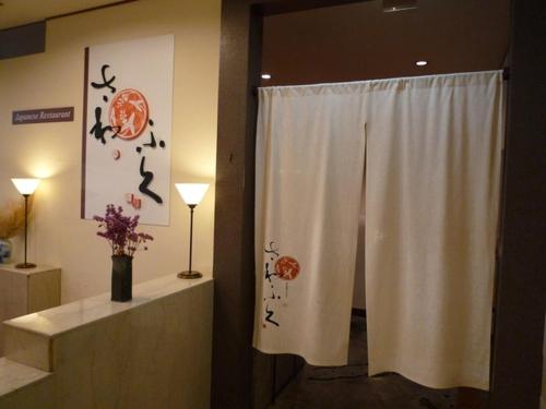 a bathroom with a shower curtain and a vase of flowers at Sky Hotel in Matsuyama