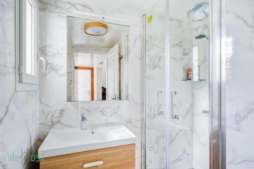 La salle de bains blanche est pourvue d'un lavabo et d'une douche. dans l'établissement Nice duplex for 6p, à Villejuif